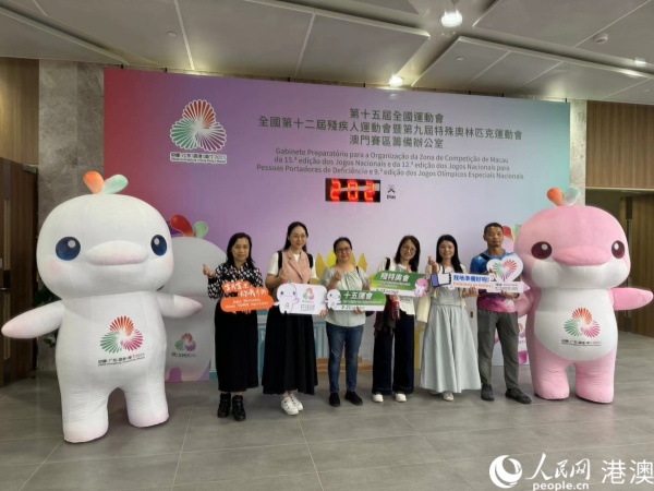 图为参加培训的澳门赛区部分志愿者在倒计时牌前，与赛事吉祥物合影。