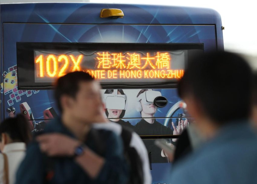 市民和旅客在横琴口岸澳门口岸区排队，准备登上前往港珠澳大桥方向的公交车。