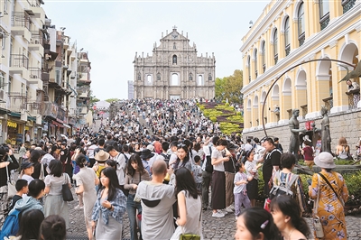 旅客在澳门大三巴牌坊前游览。
