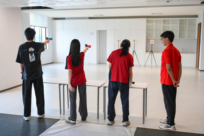 ↑图为学生们在广州市中黄港澳子弟学校运动室进行射击训练（6月19日摄）。