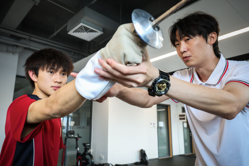 ↑图为广东现代五项运动协会教练员肖勇炫（右）纠正广州市中黄港澳子弟学校港籍生张嗣涛击剑技术细节（6月19日摄）。