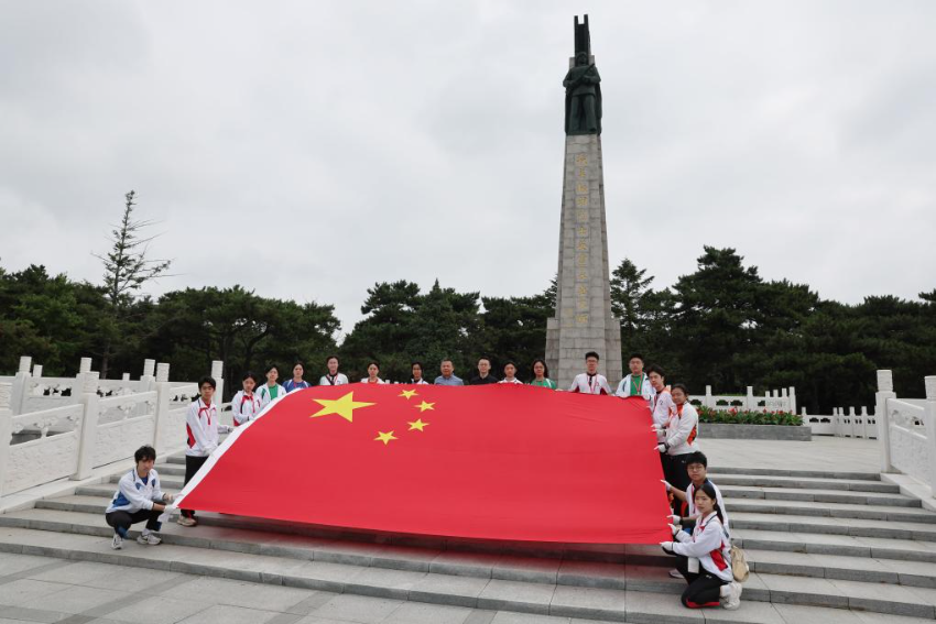 7月2日，在沈阳的抗美援朝烈士陵园，香港培侨中学的师生在纪念碑前展示五星红旗。