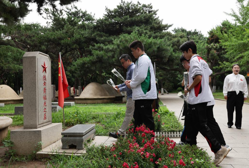7月2日，在沈阳的抗美援朝烈士陵园，香港培侨中学校长伍焕杰和学生一起向烈士墓献花。