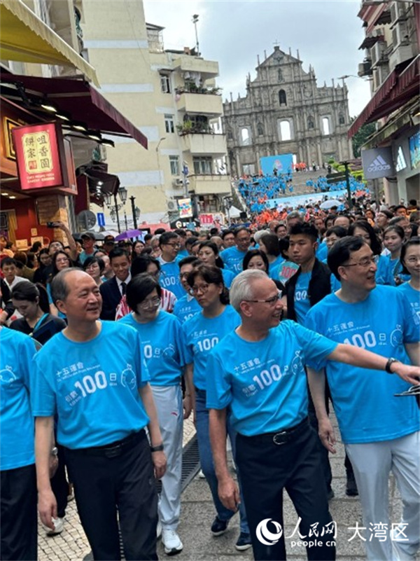 图为岑浩辉身穿蓝色运动背心，精神抖擞与众人一同从大三巴牌坊起步，参与“迎百日 健步行”活动。