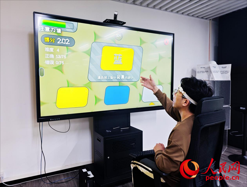 广州琶洲实验室工作人员演示脑机接口设备如何操作专注力训练游戏。